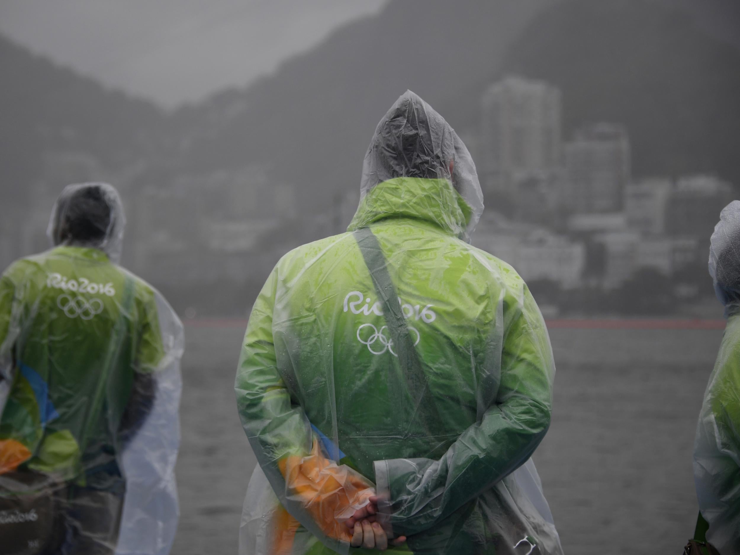 Volunteers wearing raincoats stand at the Lagoa stadium during the Rio 2016 Olympic Games