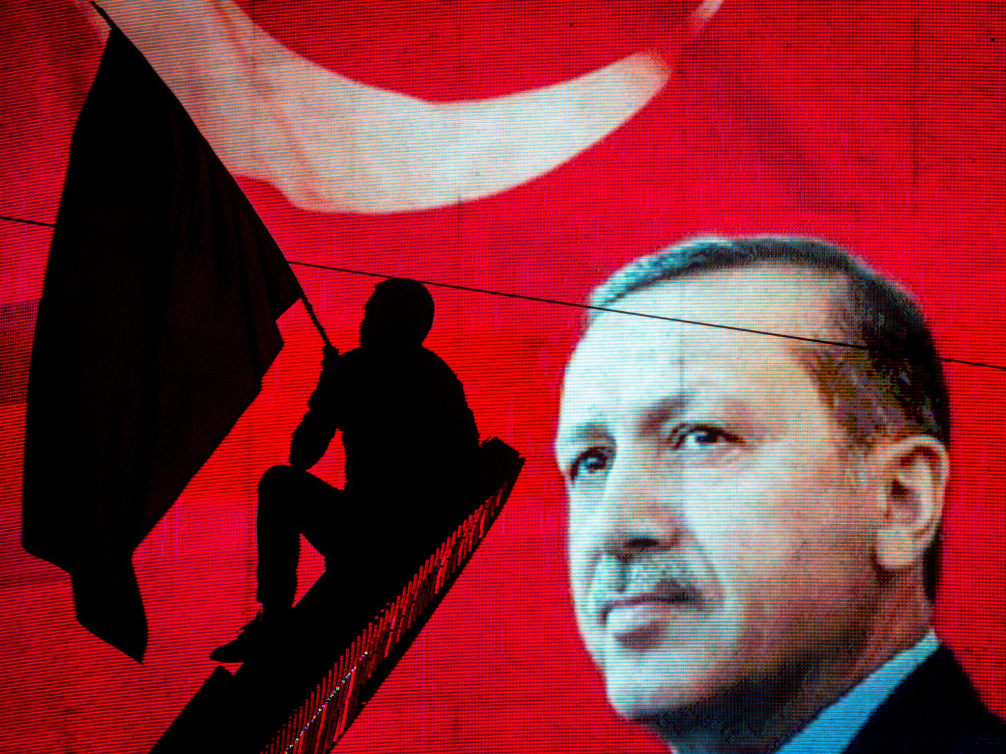 A supporter of Turkish President Recep Tayyip Erdogan waves a flag against an electronic billboard during a rally in Kizilay Square on 18 July, 2016 in Ankara, Turkey
