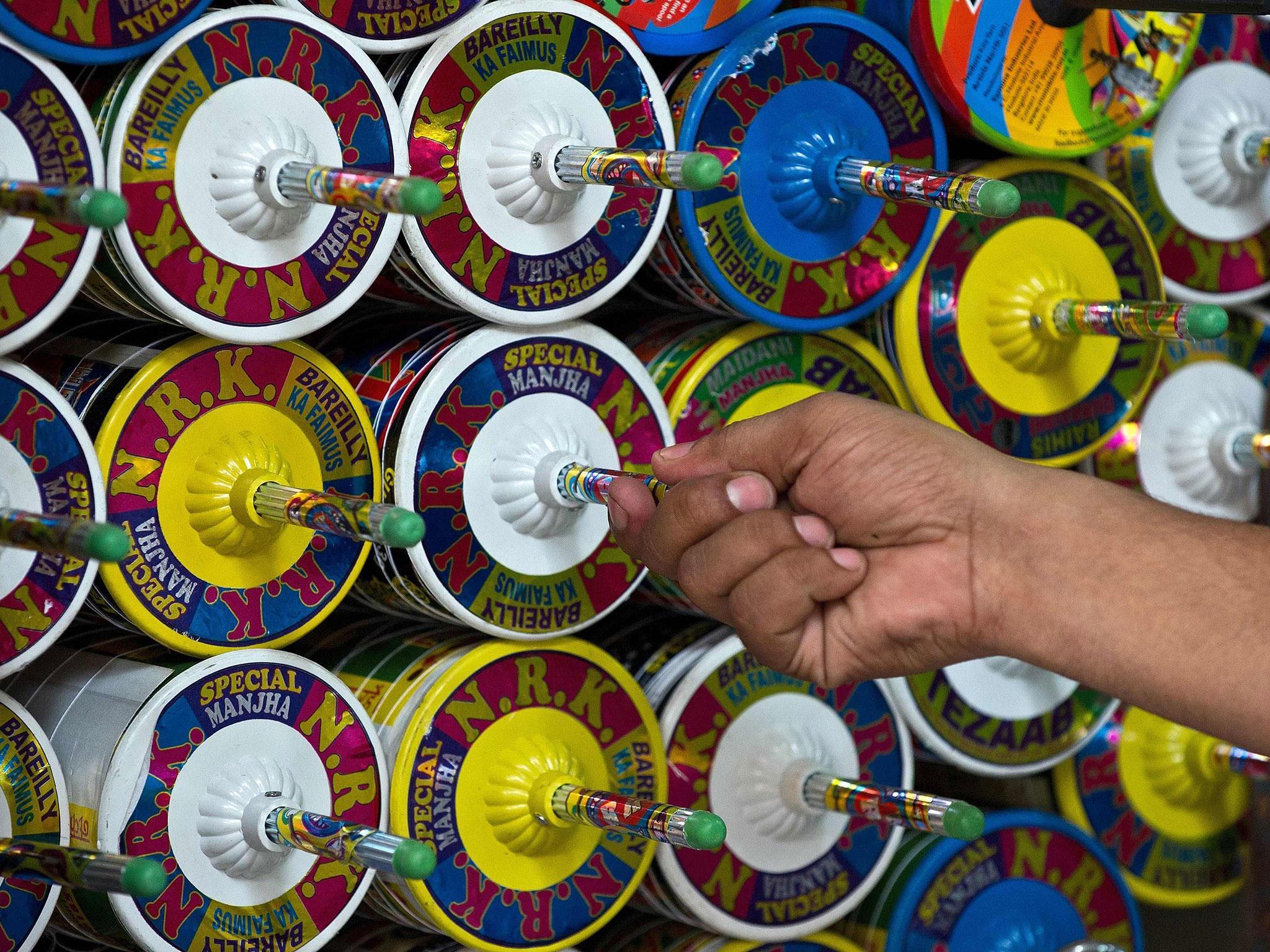 An Indian kite-maker removes a reel of kite string to be used at his shop ahead of Independence Day celebrations in New Delhi