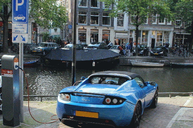 An electric Tesla car recharges on the banks of a canal in Amsterdam. The Netherlands saw an all-time high in electric cars in December this year