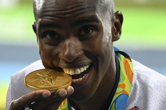 Mo Farah bites into his gold medal on the podium of the Men’s 10,000m