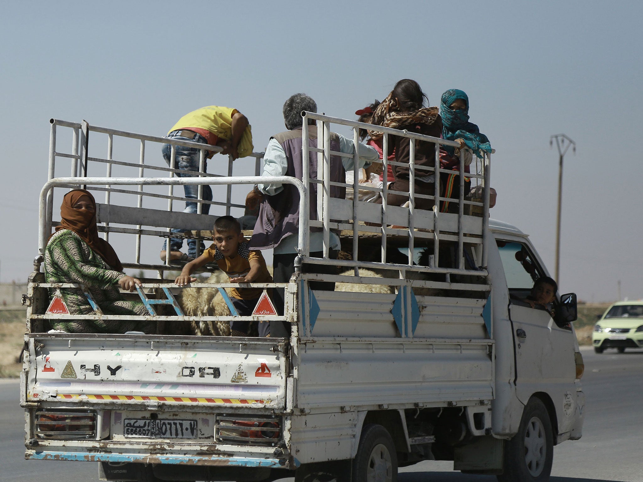 Kurdish civilians board a truck as they flee bombing in Hasakah, Syria, on 18 August