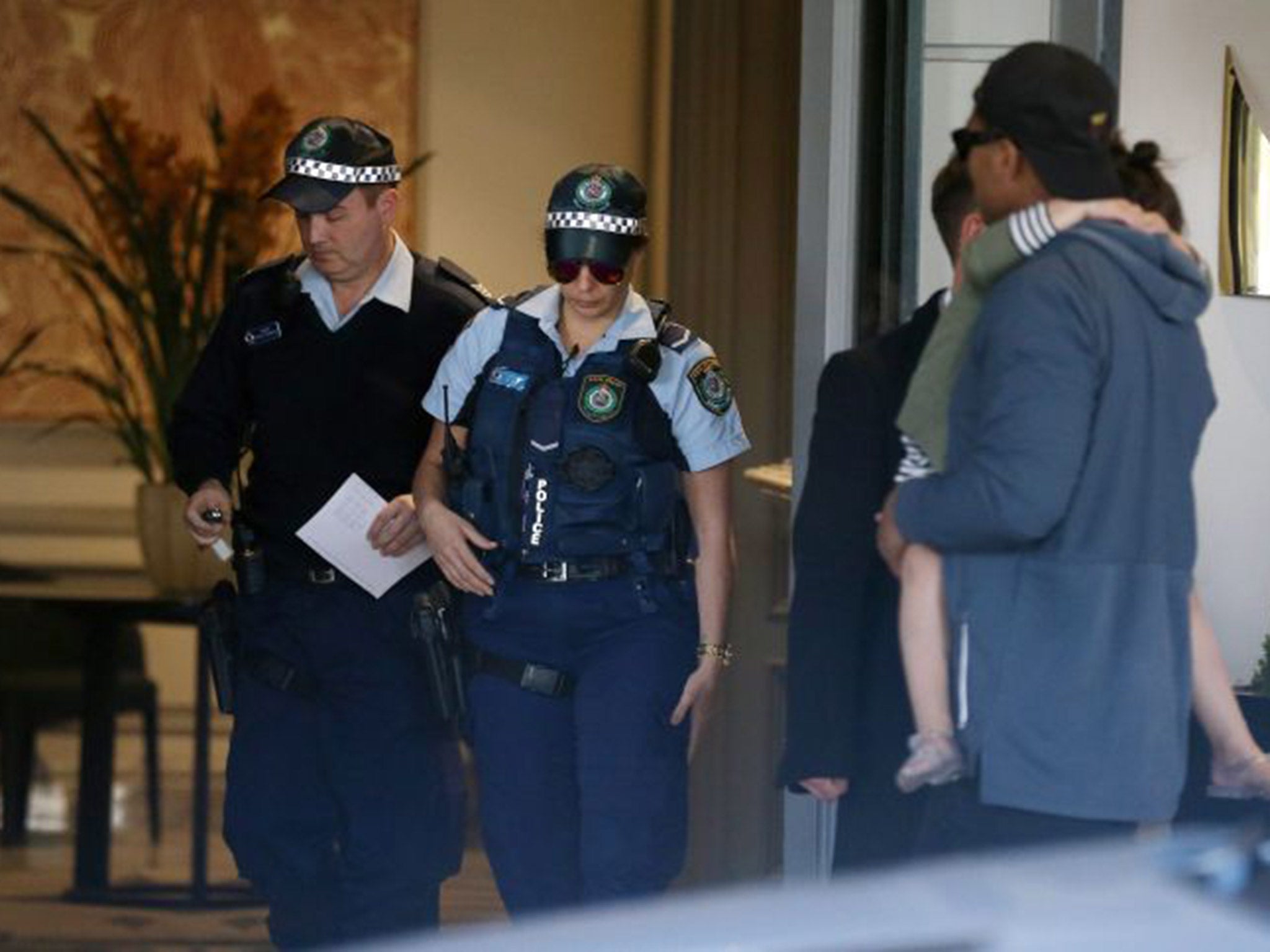 Police officers leave a hotel, where the New Zealand rugby team are staying ahead of their match against Australia