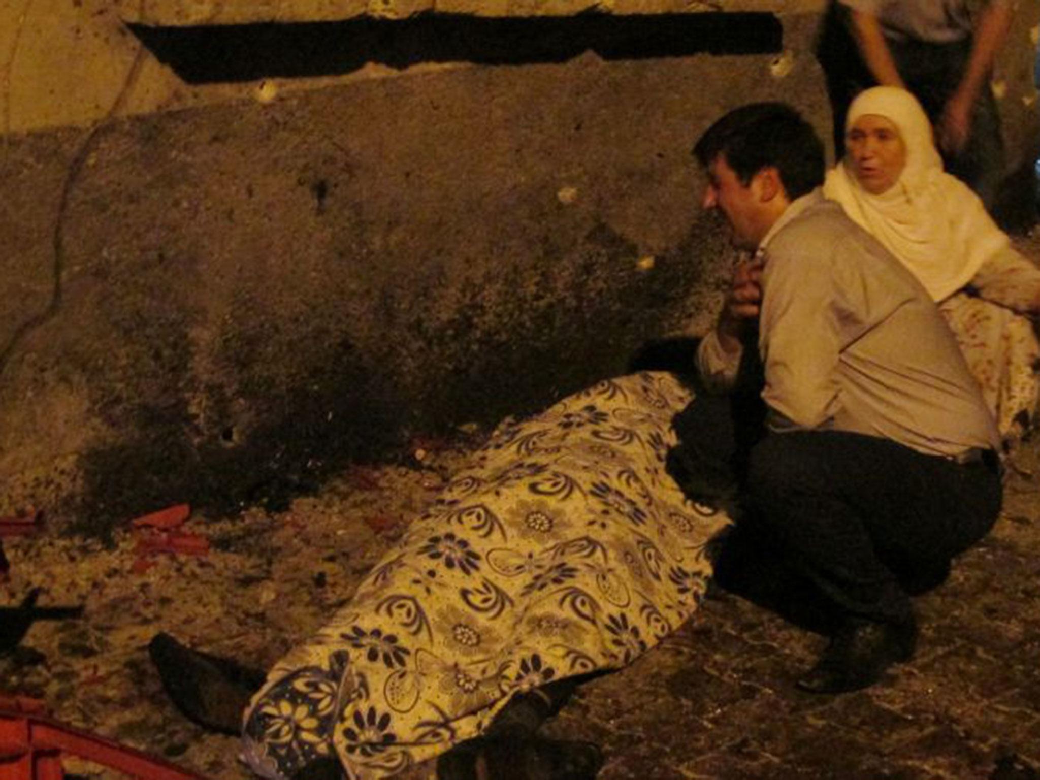 A man cries over a covered body after the explosion in Gaziantep