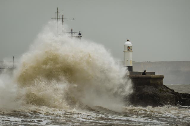 A man watches stormy conditions on the harbour wall at Porthcawl, Wales