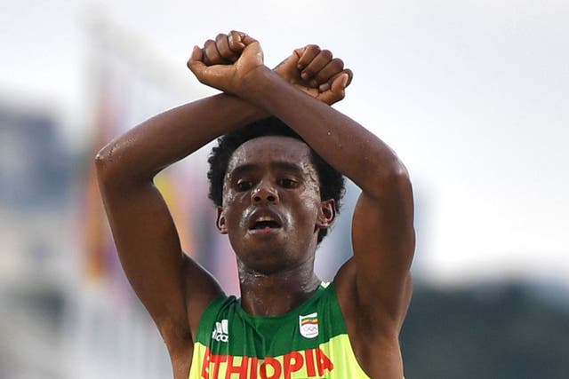 Feyisa Lilesa holding up his arms above his head in an X as a tribute to the Oromo people