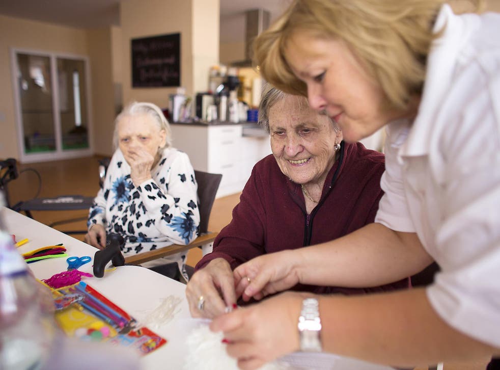 Nurse Doret Kohl (R) helps day guest Margot (C) to make handcrafts in the geriatric day care facility of the German Red Cross (DRK, or Deutsches Rotes Kreuz) at Villa Albrecht on March 11, 2013 in Berlin, Germany