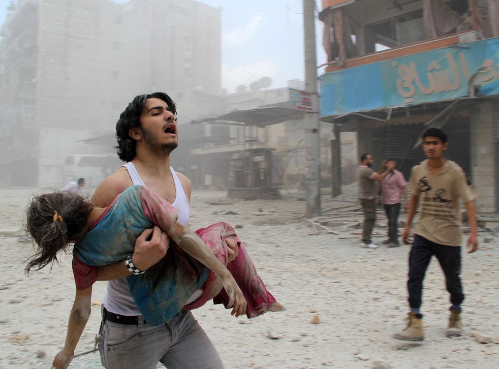 A man carries a young girl who was injured in a reported barrel-bomb attack by government forces on 3 June, 2014 in Kallaseh district in the northern city of Aleppo
