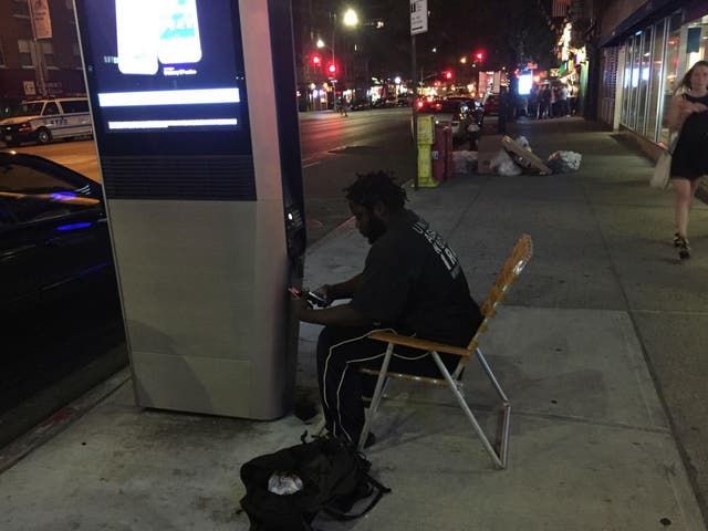 Jay, a homeless man, settles for the evening by a LinkNYC hotspot station on Third Avenue