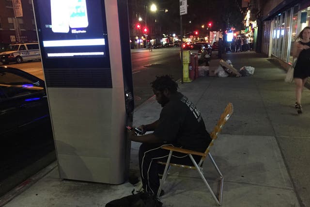 Jay, a homeless man, settles for the evening by a LinkNYC hotspot station on Third Avenue