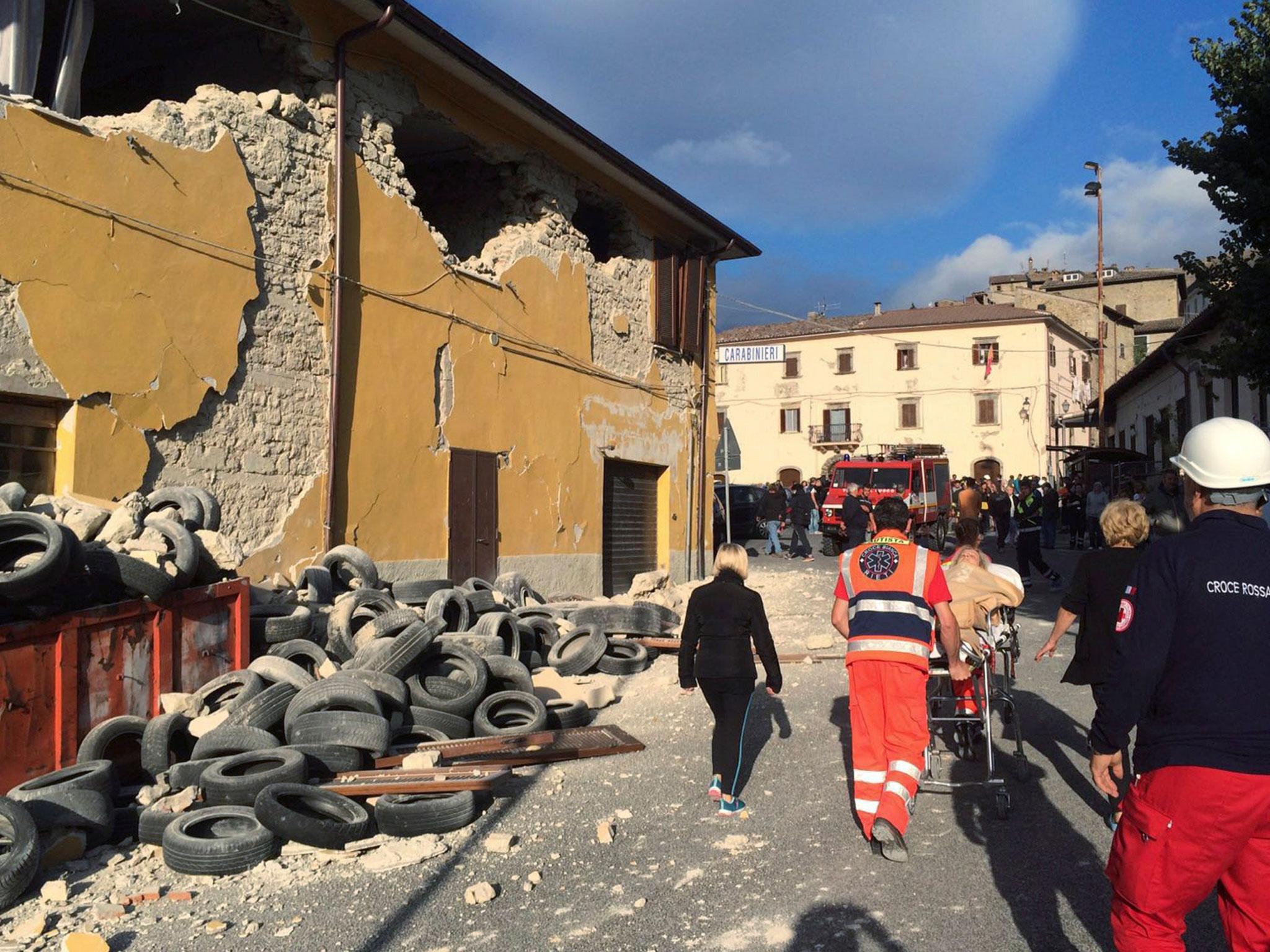 Rescuers and people walk along a road following an earthquake in Accumoli di Rieti,