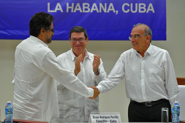 Colombia's Humberto de la Calle (right) and the FARC Commander Ivan Marquez (left) shake hands upon the signing of the agreement at the Convention Palace in Havana