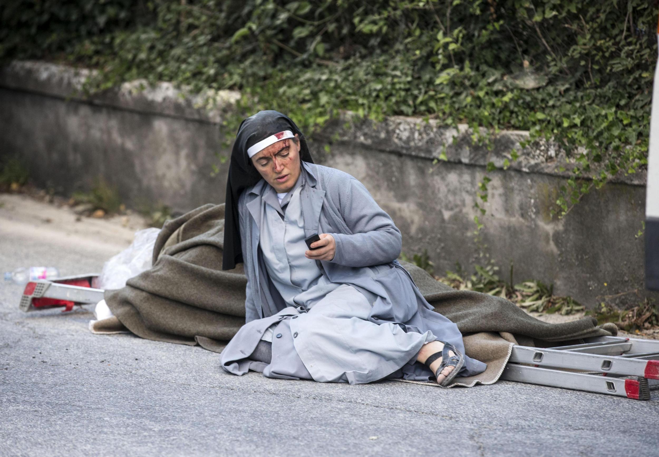 Sister Mariana, from Albania, checks her mobile phone as she lies near a victim