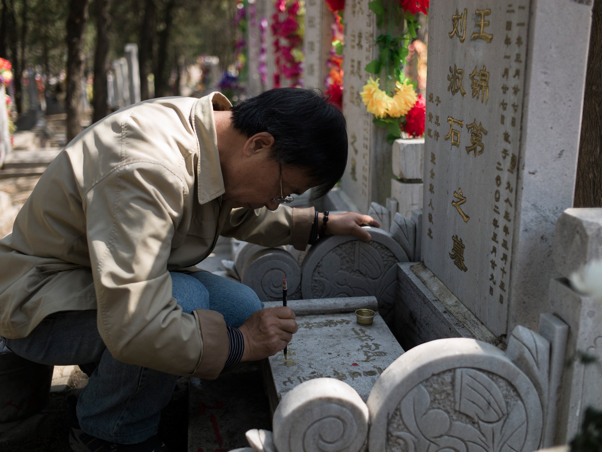 A man repaints the letters on a grave during the 'Qingming' festival, or Tomb Sweeping Day, at a cemetary in Babaoshan in Beijing