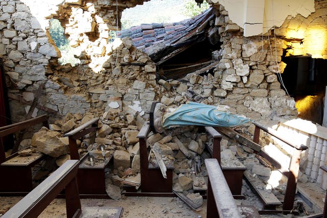 A damaged Virgin Mary statue is seen in a church following an earthquake at Cossito near Amatrice