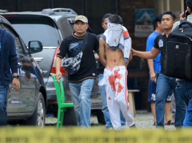 An Indonesian plainclothes policeman detains a terrorist suspect (C) after an attempted suicide bombing at St. Yoseph Catholic Church in Medan, Indonesia, 28 August 2016
