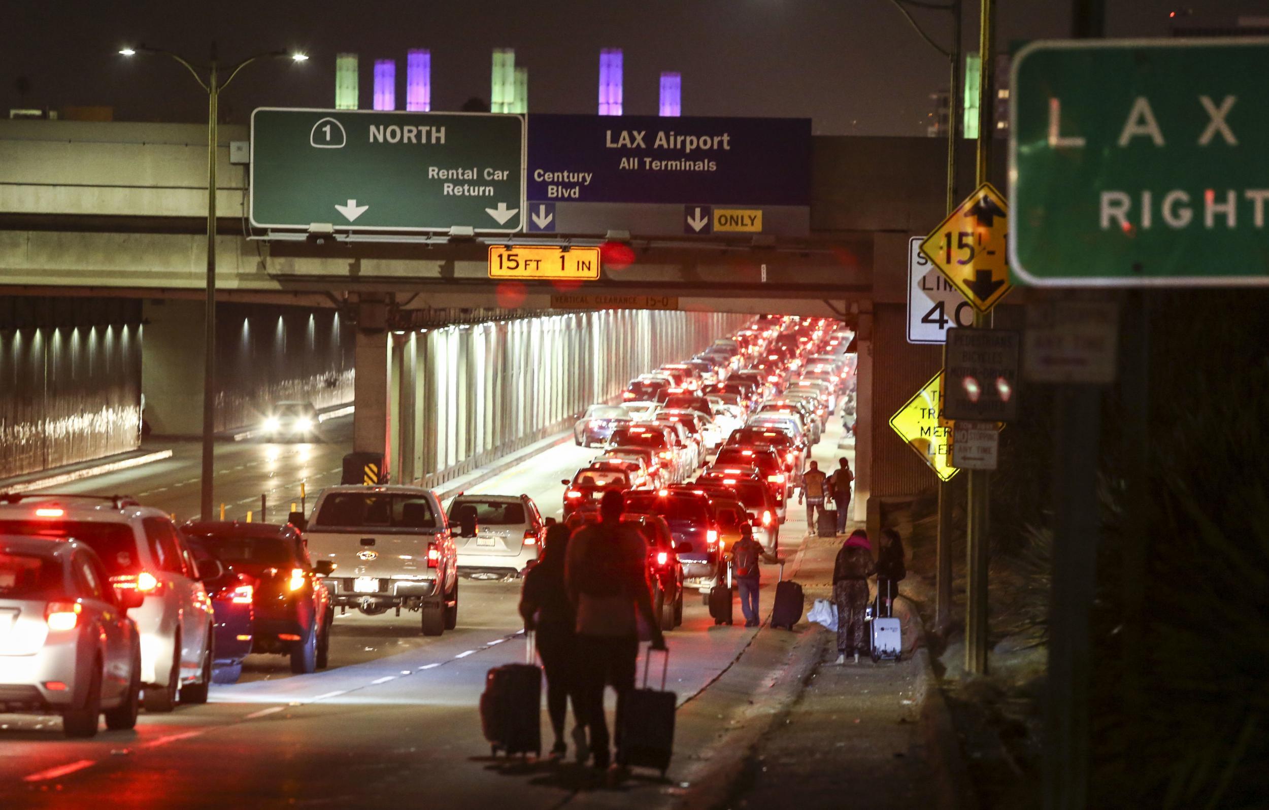Passengers pull their luggage and walk toward Los Angeles International Airport on Sunday, August 28, 2016.