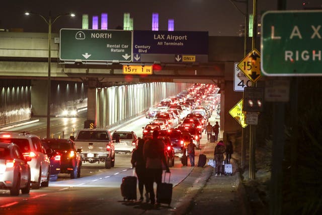 Passengers pull their luggage and walk toward Los Angeles International Airport on Sunday, August 28, 2016.