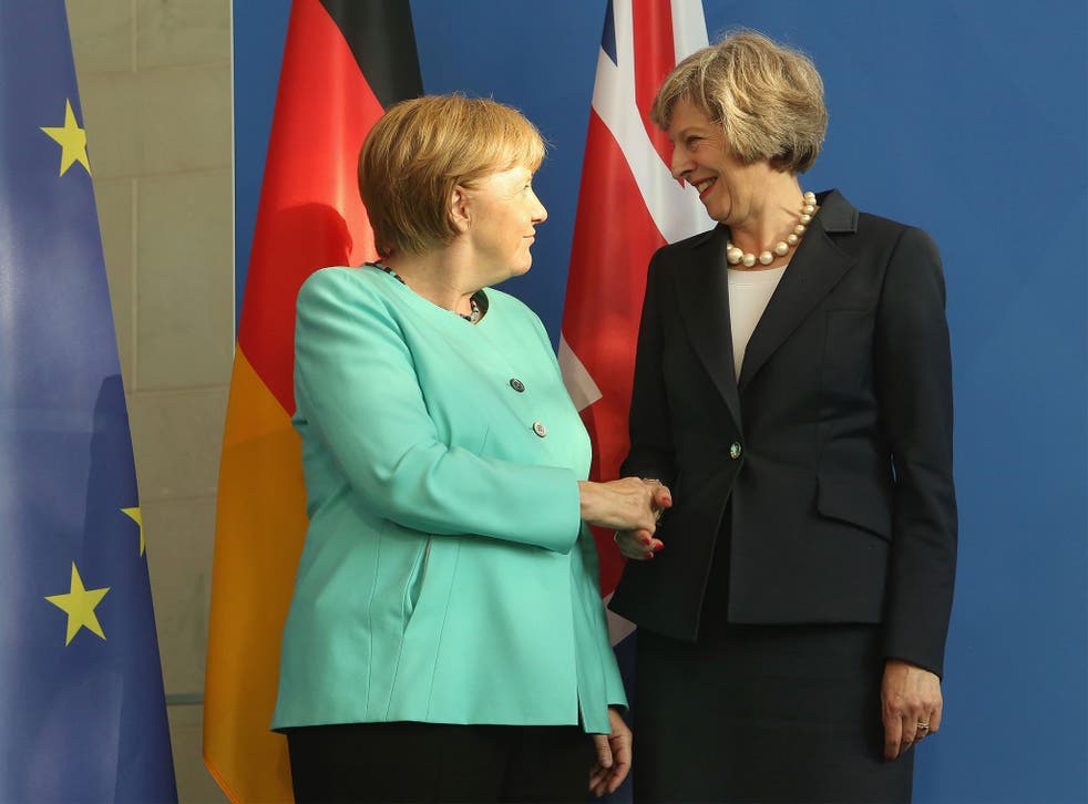 Theresa May and German Chancellor Angela Merkel shake hands at a conference last month