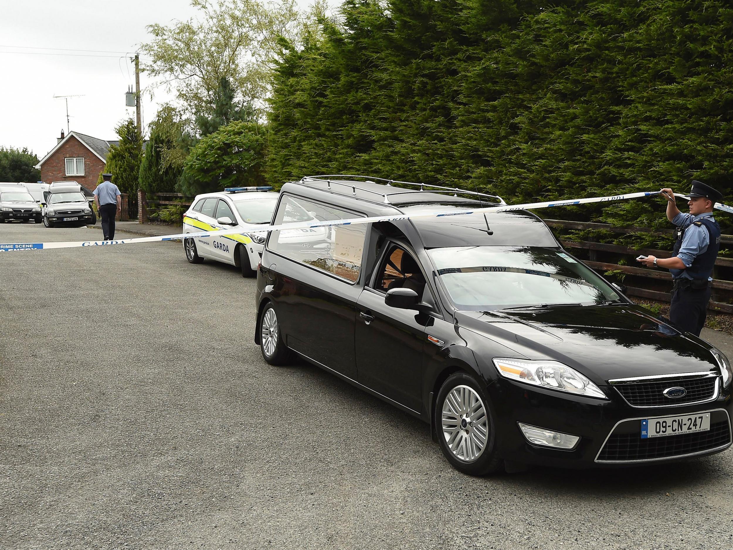 A Garda technical officer lifts tape as a hearse leaves the scene at Oakdene, Barconey, Ballyjamesduff in Cavan, where a family of five were found dead in their countryside home