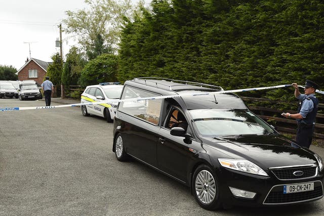 A Garda technical officer lifts tape as a hearse leaves the scene at Oakdene, Barconey, Ballyjamesduff in Cavan, where a family of five were found dead in their countryside home