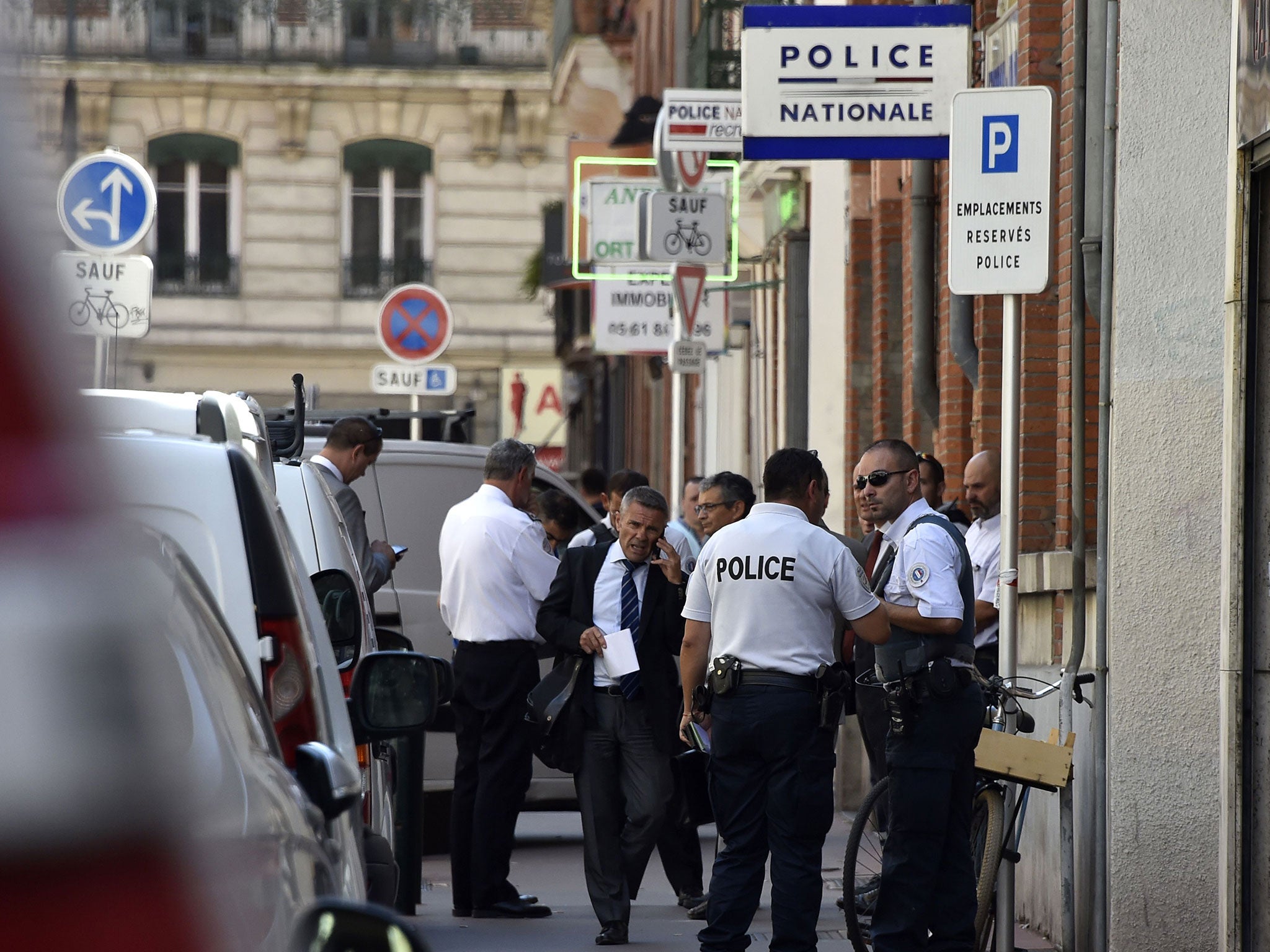 French police officers standing guard in front of a station where an officer was stabbed in Toulouse on 30 August
