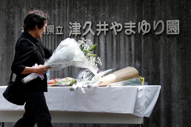 A woman offers flowers to mourn the victims at Sagamihara, close to the location of their murder