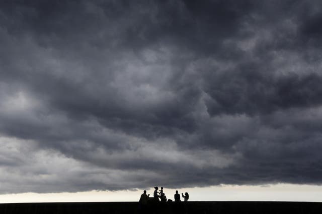 Storm clouds are seen in the sky as people sit on Havana's seafront boulevard El Malecon, Cuba