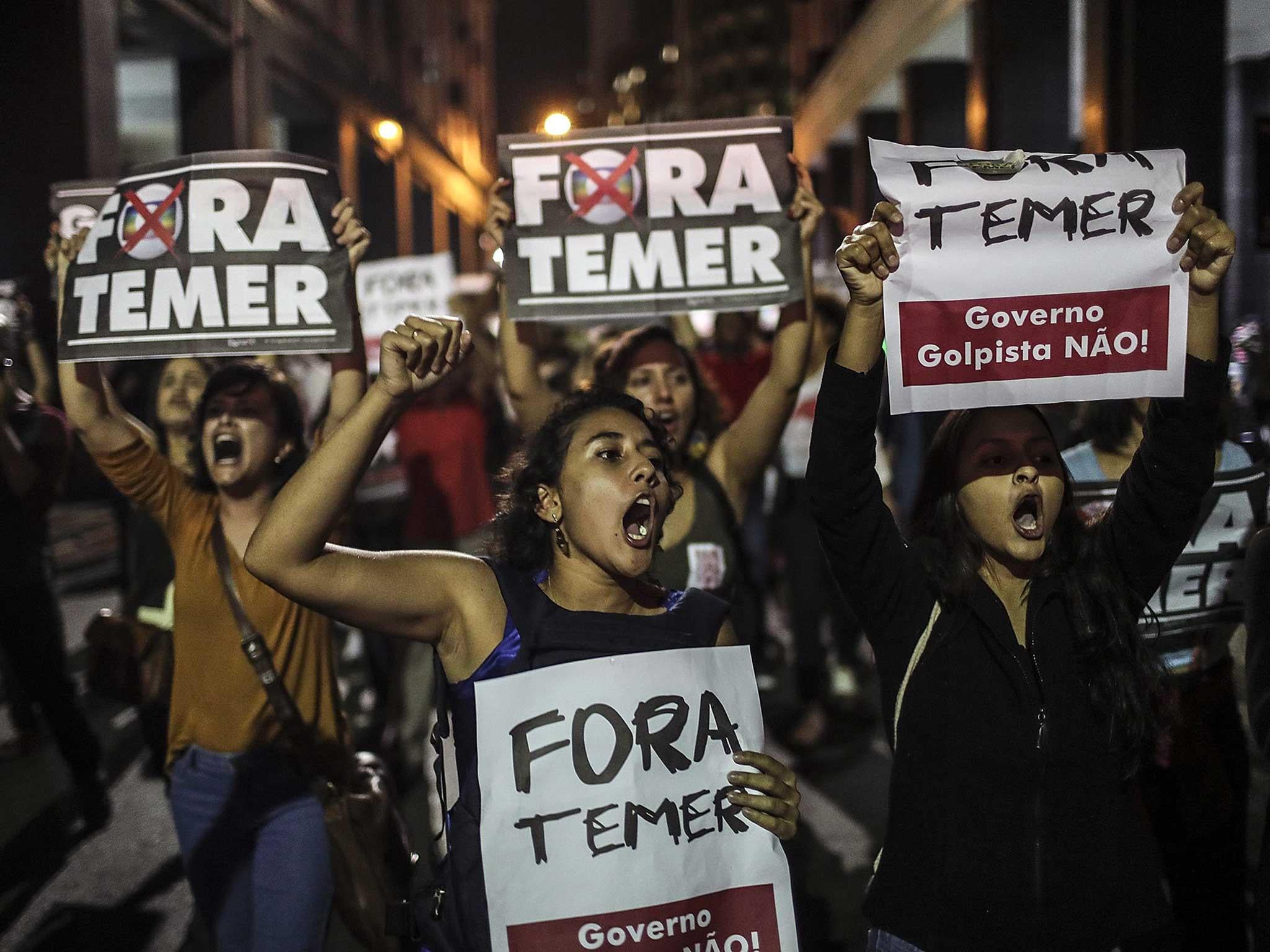 Protesters in Brazil hold signs saying ’Out with Temer’
