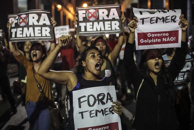 Protesters in Brazil hold signs saying ’Out with Temer’