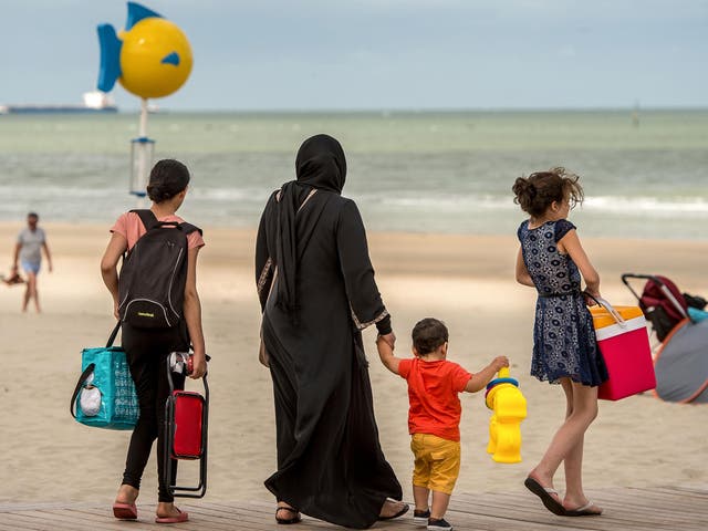 A Muslim woman walks on a beach