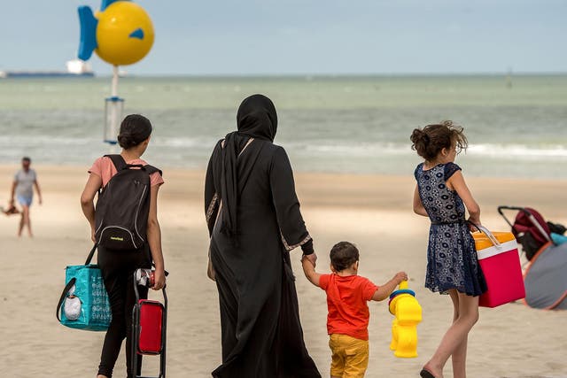 A Muslim woman walks on a beach