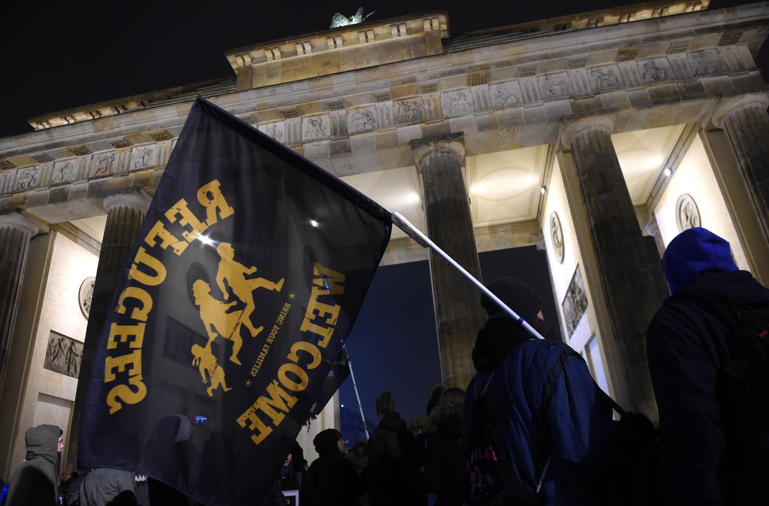 A German protester holds a ‘refugees welcome’ flag at a demonstration in Berlin