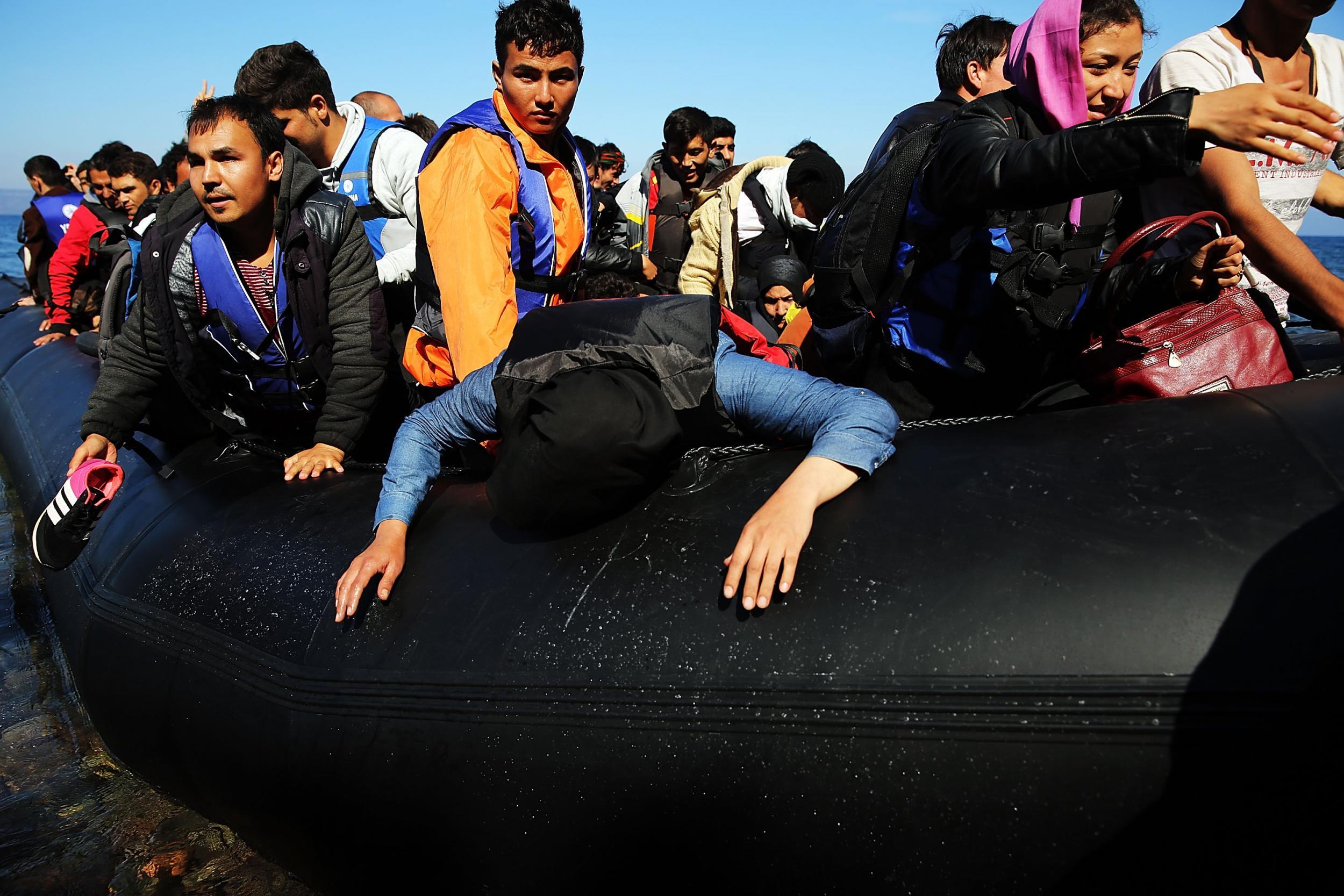 Refugees disembark from a raft after arriving in Sikaminias, Greece