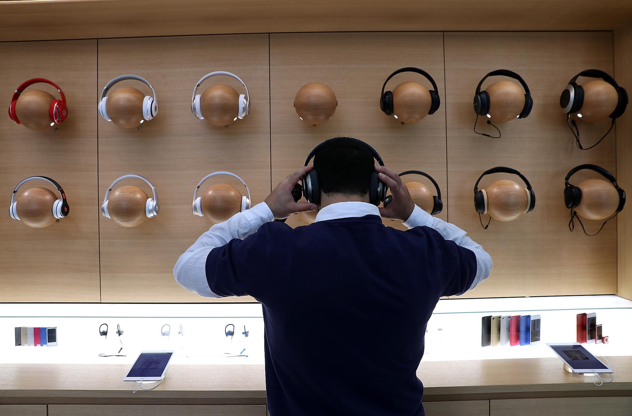 An Apple Store employee tries on a pair of headphones during a press preview of the new flagship Apple Store on May 19, 2016 in San Francisco, California