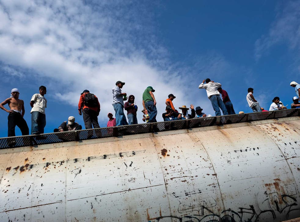 Dozens of Central American immigrants ride atop a cargo train passing through the border area in the south of Mexico, on 25 May 2010