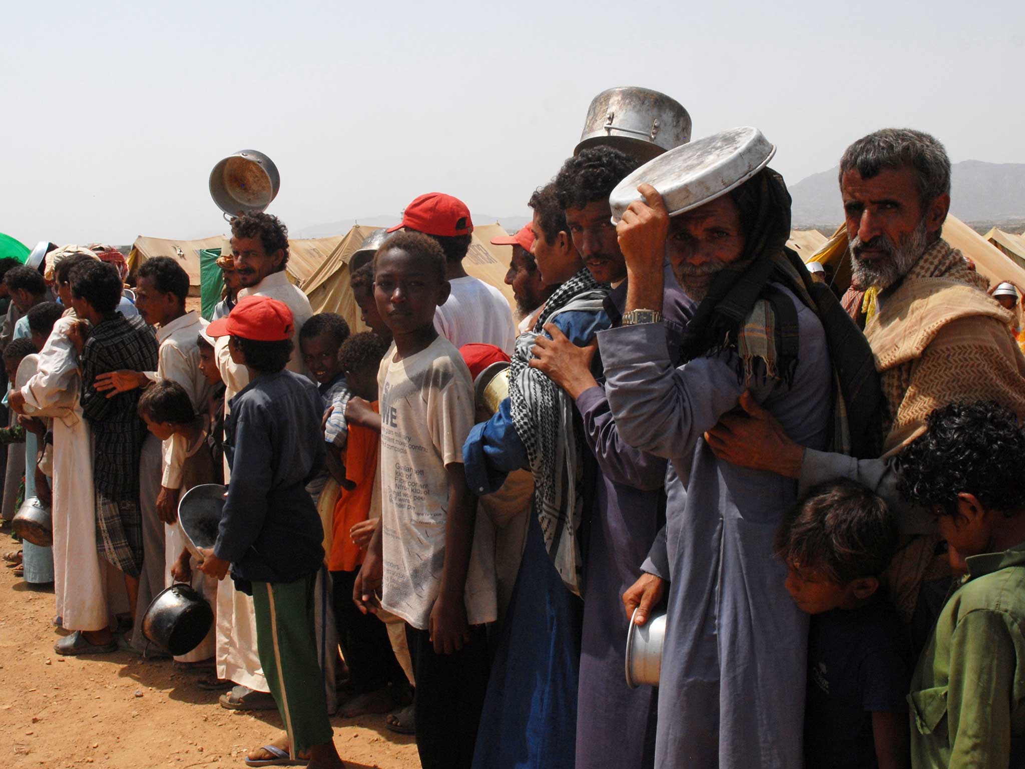 Yemeni refugees queue to get food aid at the Marzaq internally displaced people's camp in Harad in the northwestern province of Hajjah 2009