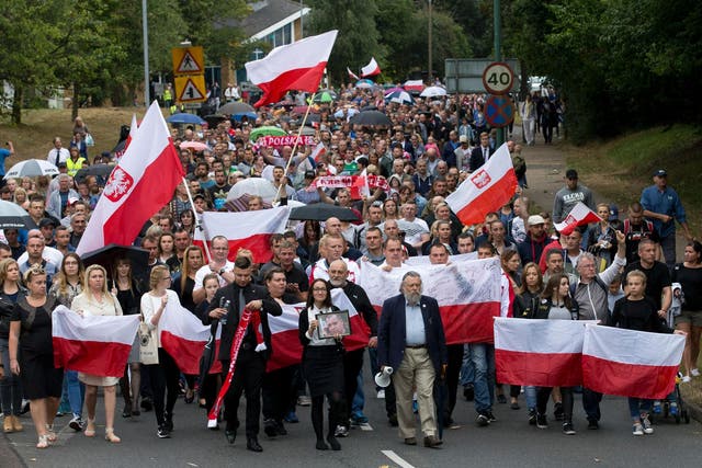 Marchers wave Polish flags as they march through Harlow exactly a week after the killing of Arek Jozwik