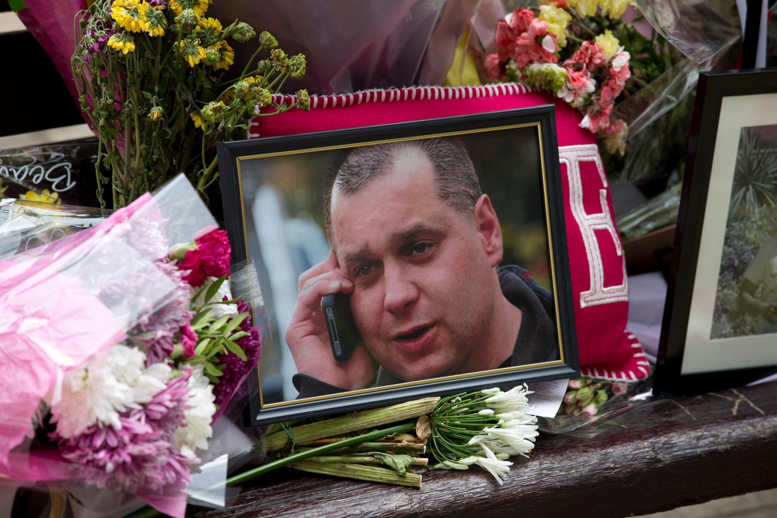 A picture of Arek Jozwik at the centre of a floral tribute on the side of his killing
