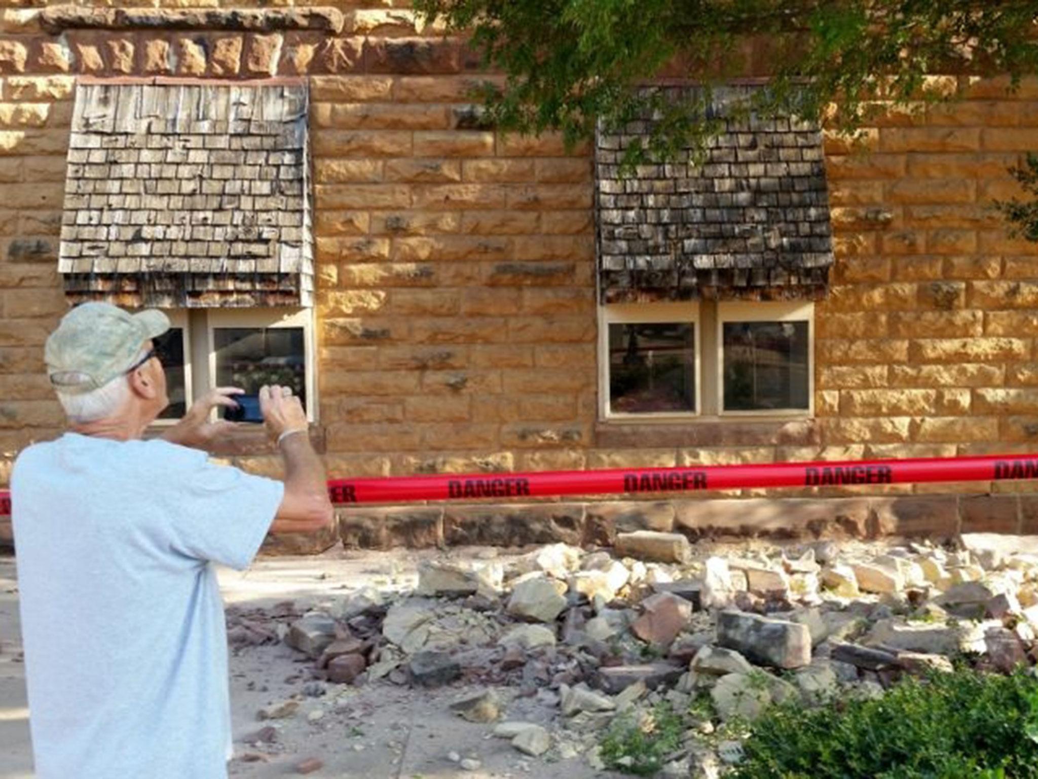 Pawnee resident Steve Gibson takes photos of the earthquake damage to a building in downtown Pawnee