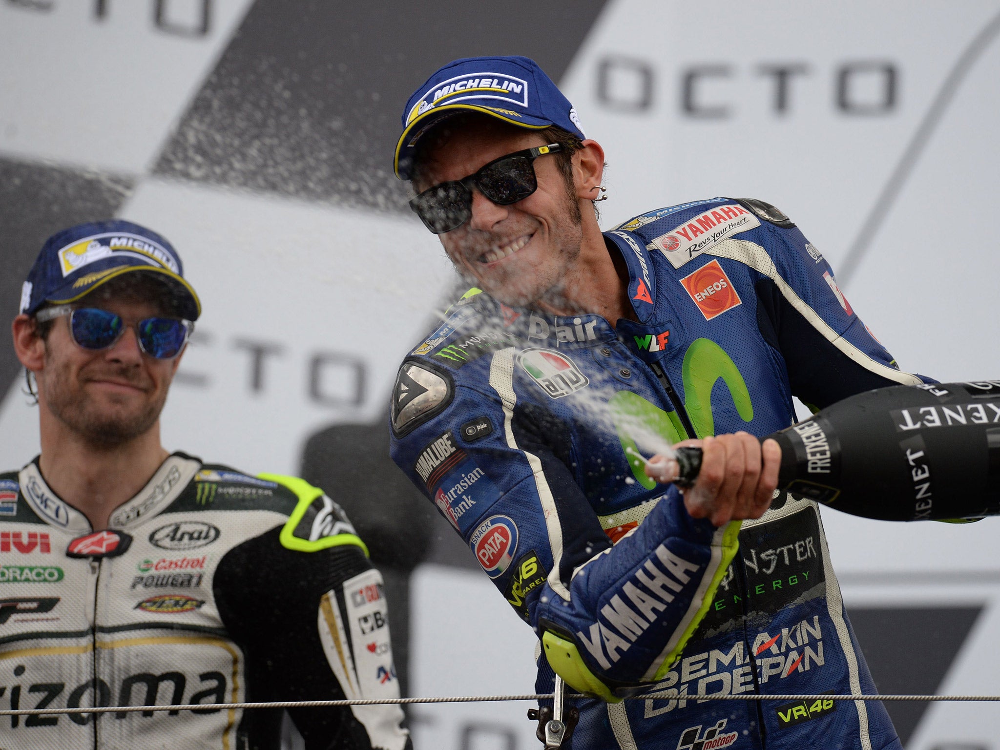 Valentino Rossi celebrates on the podium alongside Cal Crutchlow