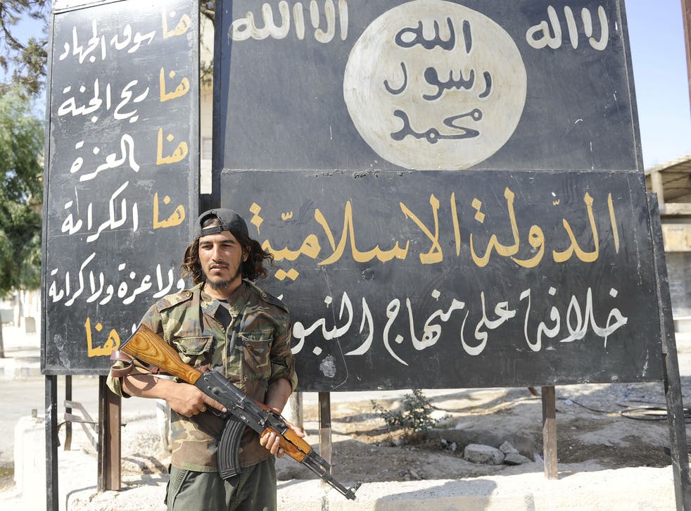 A Free Syrian Army fighter stands by an Isis sign in Jarablus after militants were driven out of the Syrian city