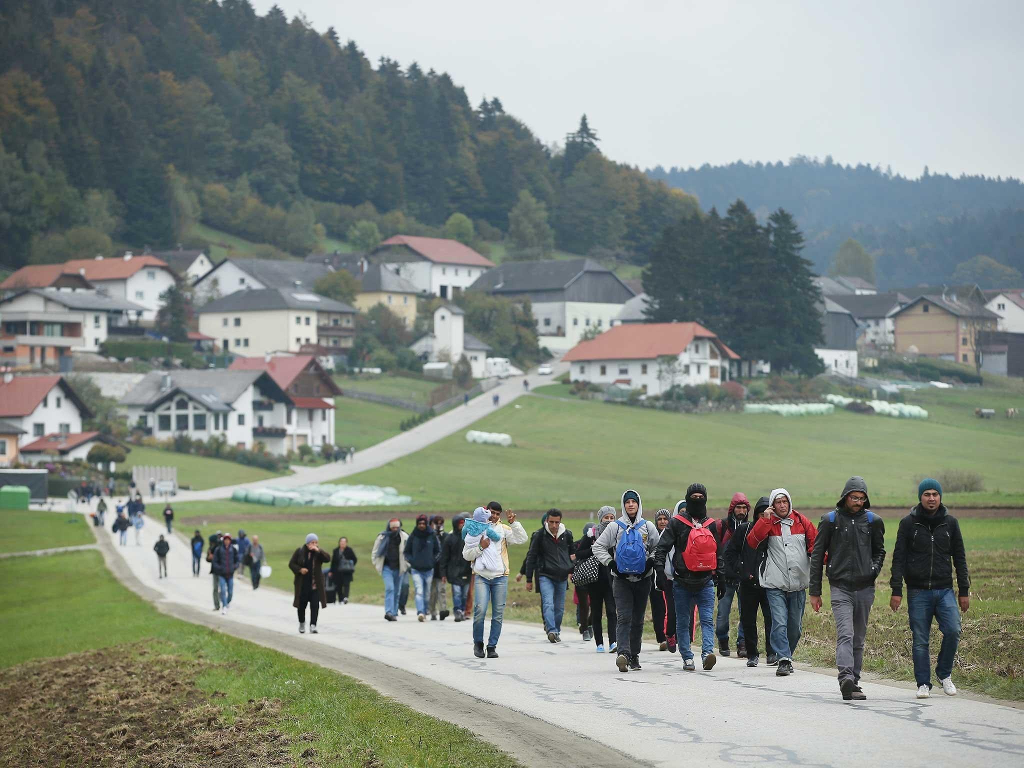 Refugees who had arrived via buses chartered by Austrian authorities walk towards the border to Germany near Mistlberg, Austria