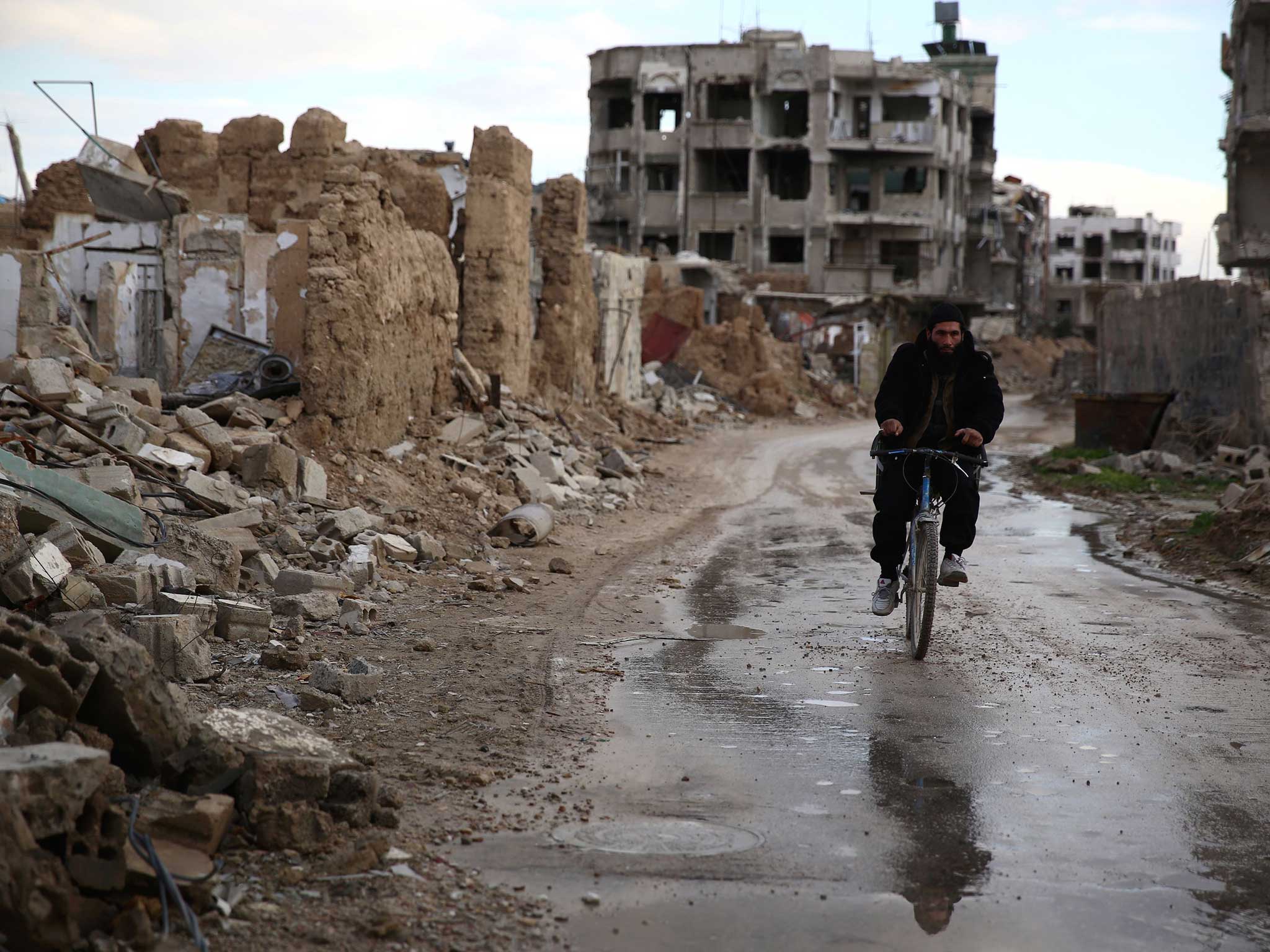 A Syrian man rides a bike in the neighbourhood of Jobar, on the eastern outskirts of the capital Damascus