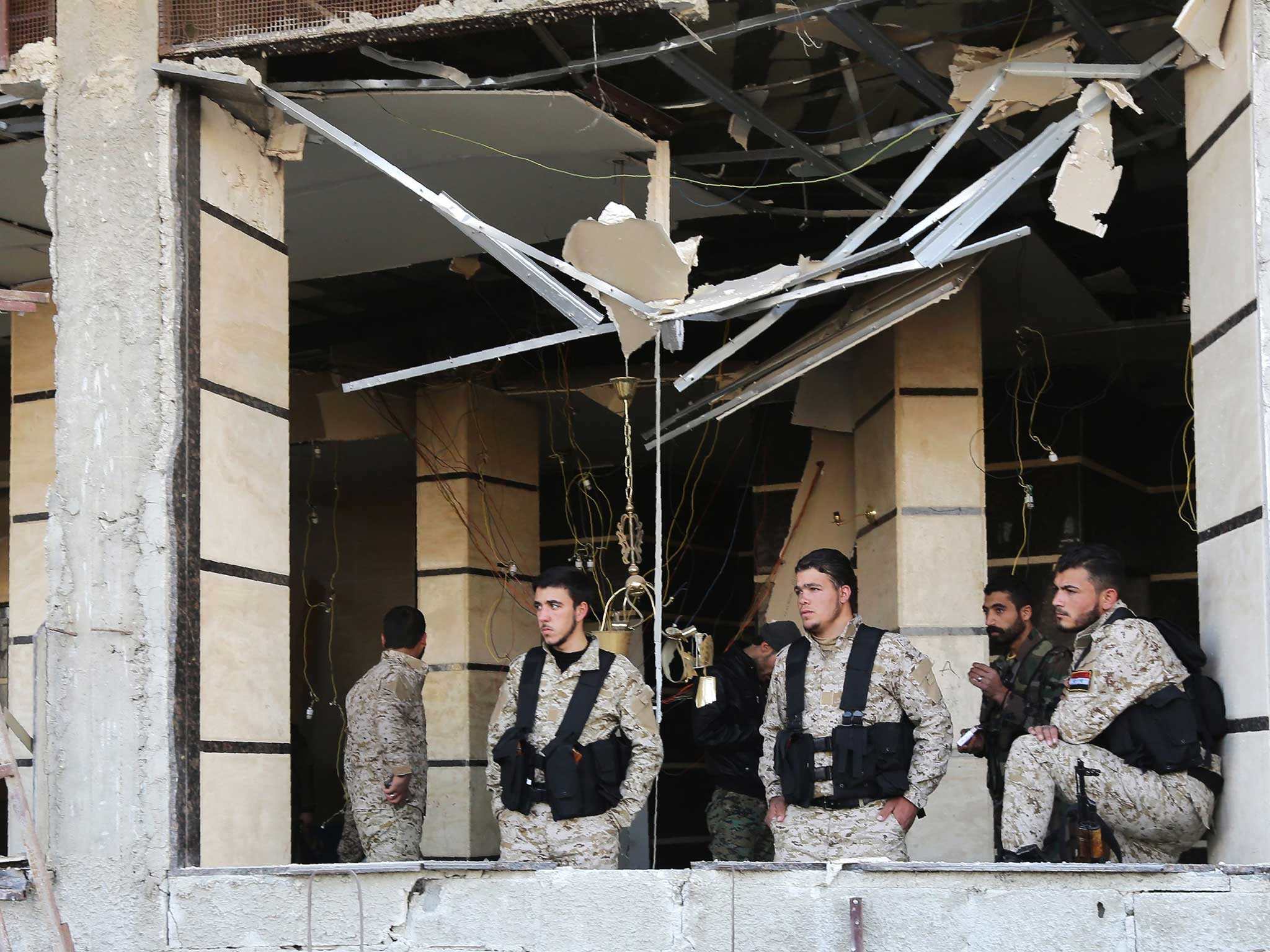 Syrian pro-government forces inspect damage following suicide bombings in the area of a revered Shiite shrine in the town of Sayyida Zeinab on the outskirts of Damascus