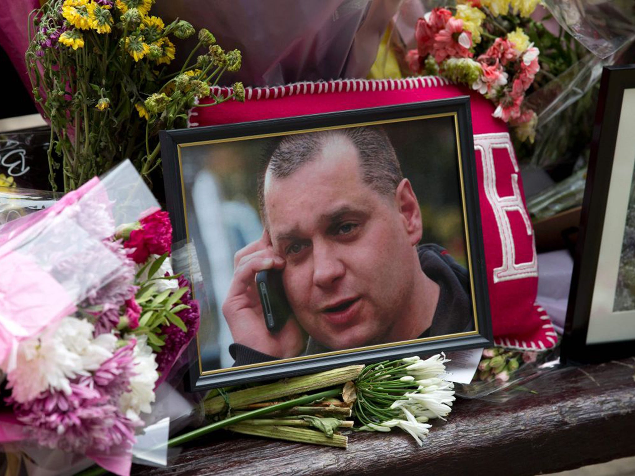 A photo of Arek Jozwik amid floral tributes left near the spot where he was fatally injured