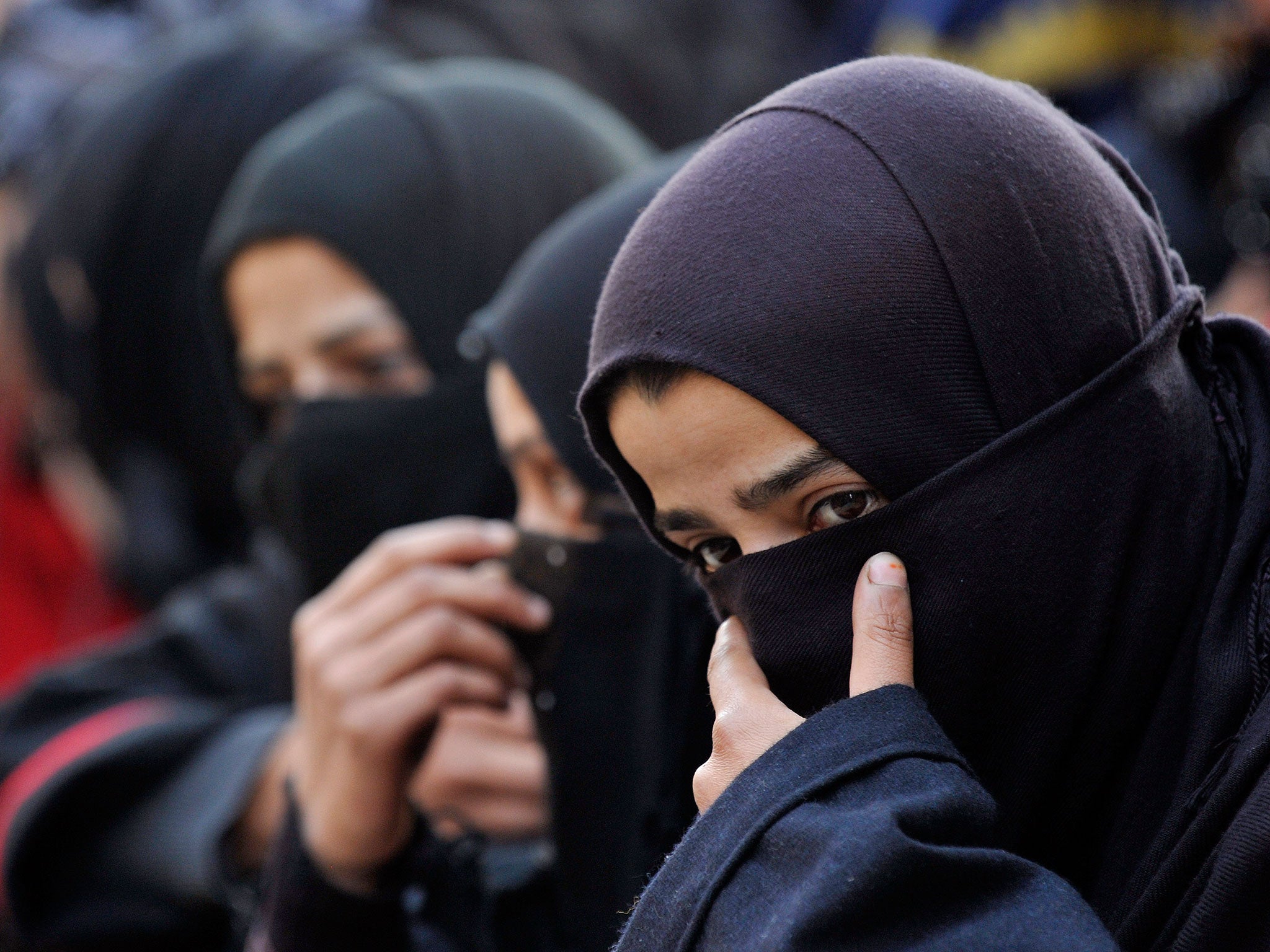 Kashmiri Shia Muslim women and girls watch a religious procession in downtown Srinagar on December 6,2011