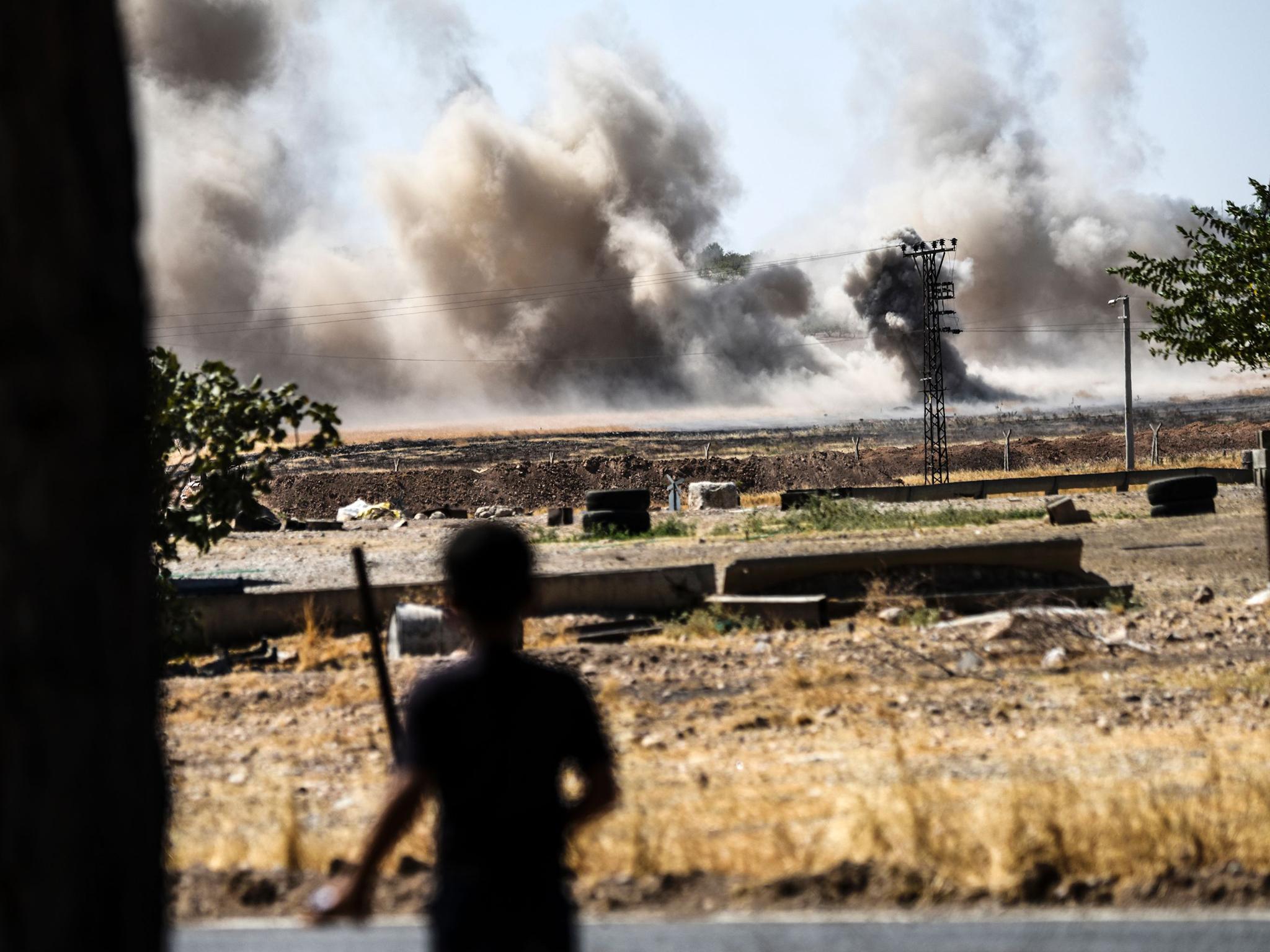 A young boy watches smoke rising over Jarabulus from the Turkish-Syrian border town of Karkamis on 1 September