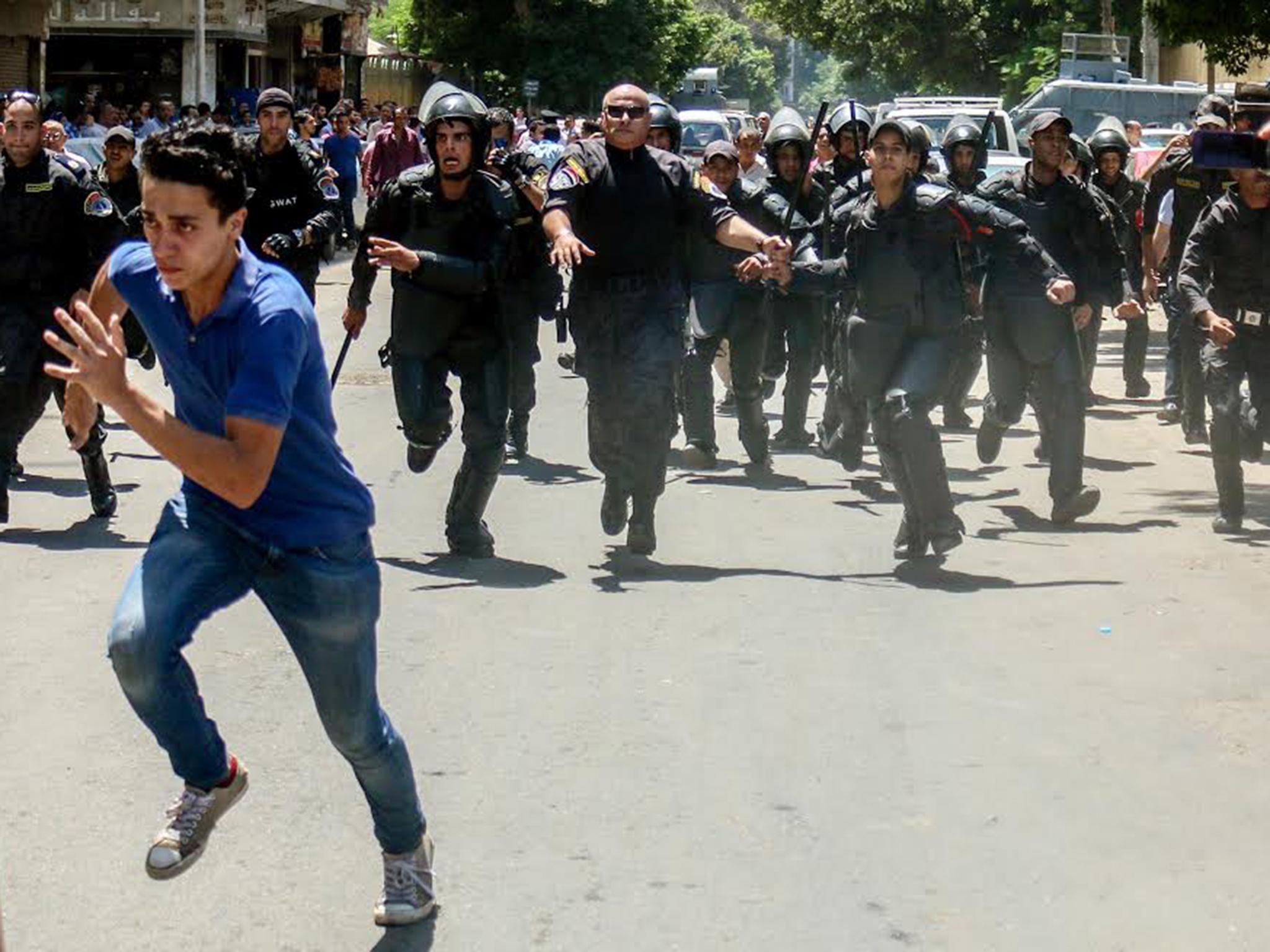 Egyptian security forces chase a student who was protesting after the cancellation of exams, in front of the Ministry of Education