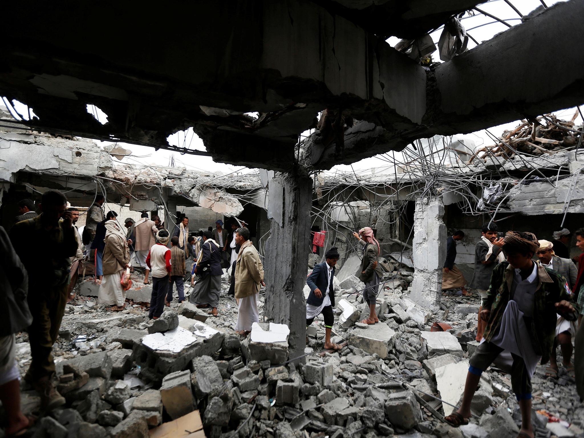 People gather at a building destroyed by Saudi-led air strikes in the northwestern city of Amran, Yemen